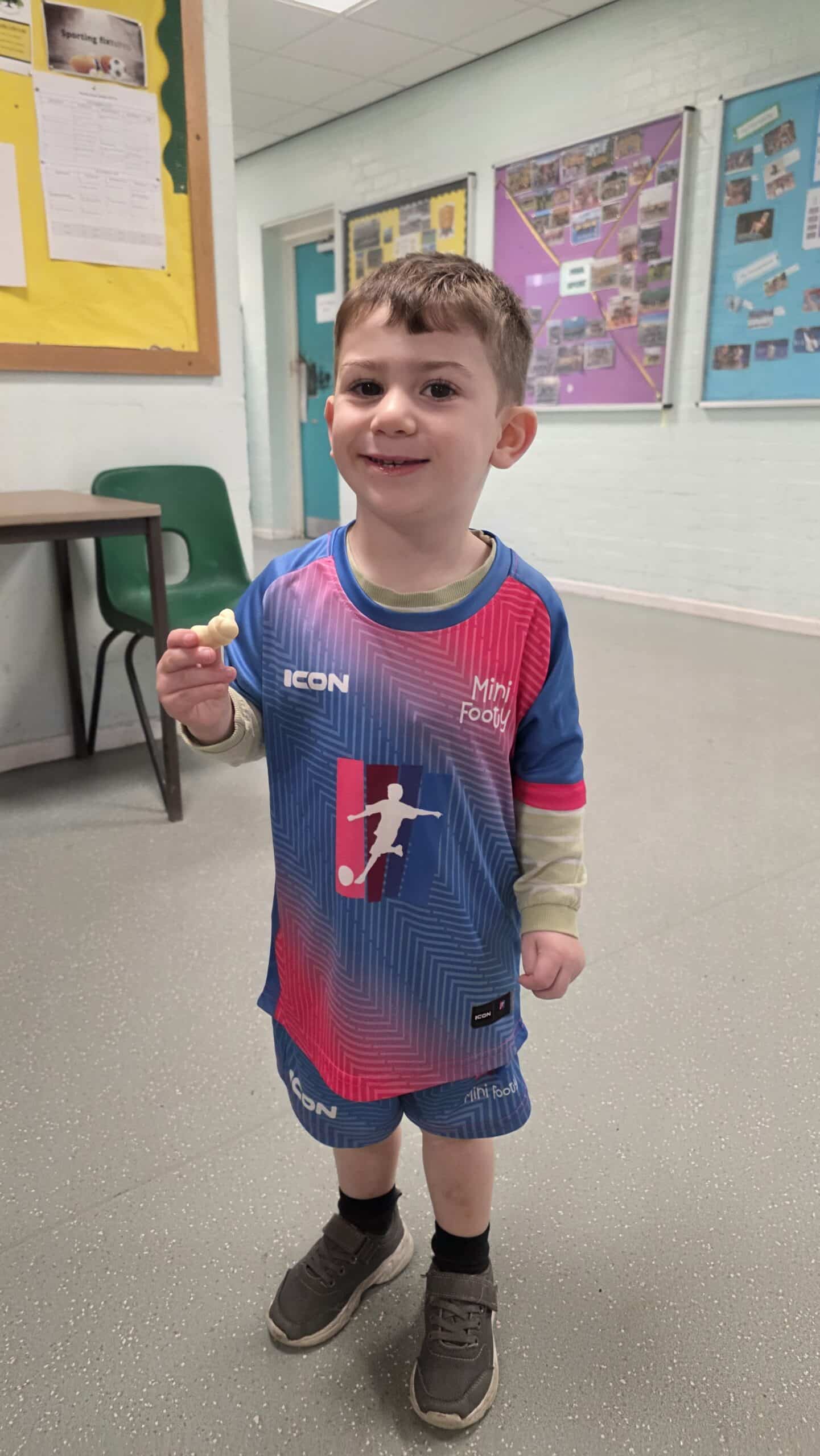 Child wearing a pink and blue Mini Footy kit